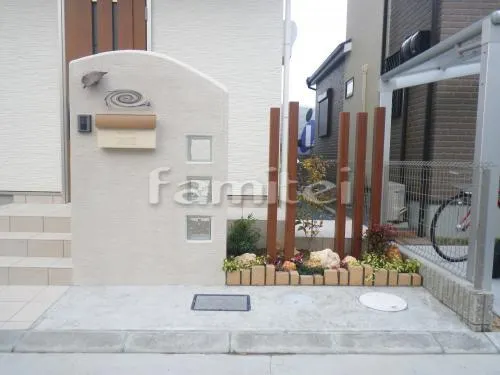 茨木市 外構工事 玄関ポーチ階段 床タイル貼り ホワイト門柱 塗り壁 ガラスブロック 木製調デザインアルミ角柱 表札灯ライト 郵便受けポスト レンガ花壇 植栽 下草 低木 ゴロタ石 カーポート 駐車場ガレージ 土間コンクリート レンガ目地 境界フェンス塀